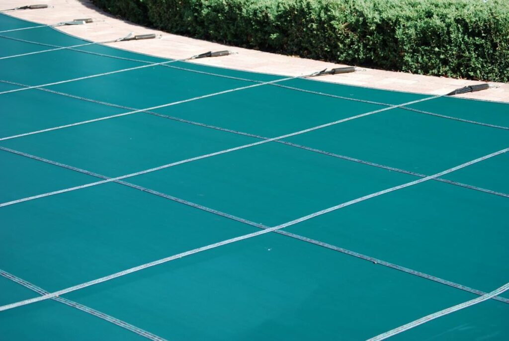 A green cover sits on top of a closed pool 