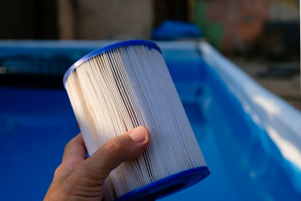 A hand holds a pool filter cartridge