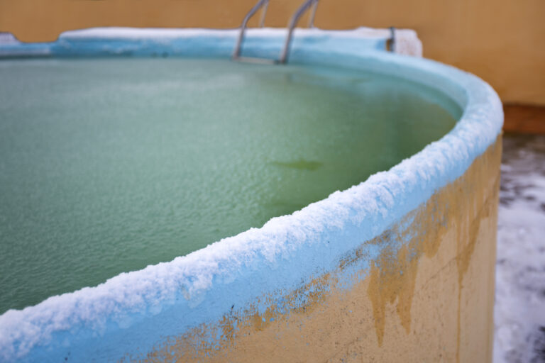 A swimming pool with surface water frozen after a winter storm.