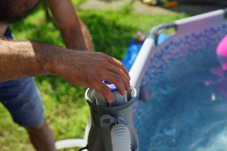 A pool maintenance technician changes a swimming pool’s filter system.
