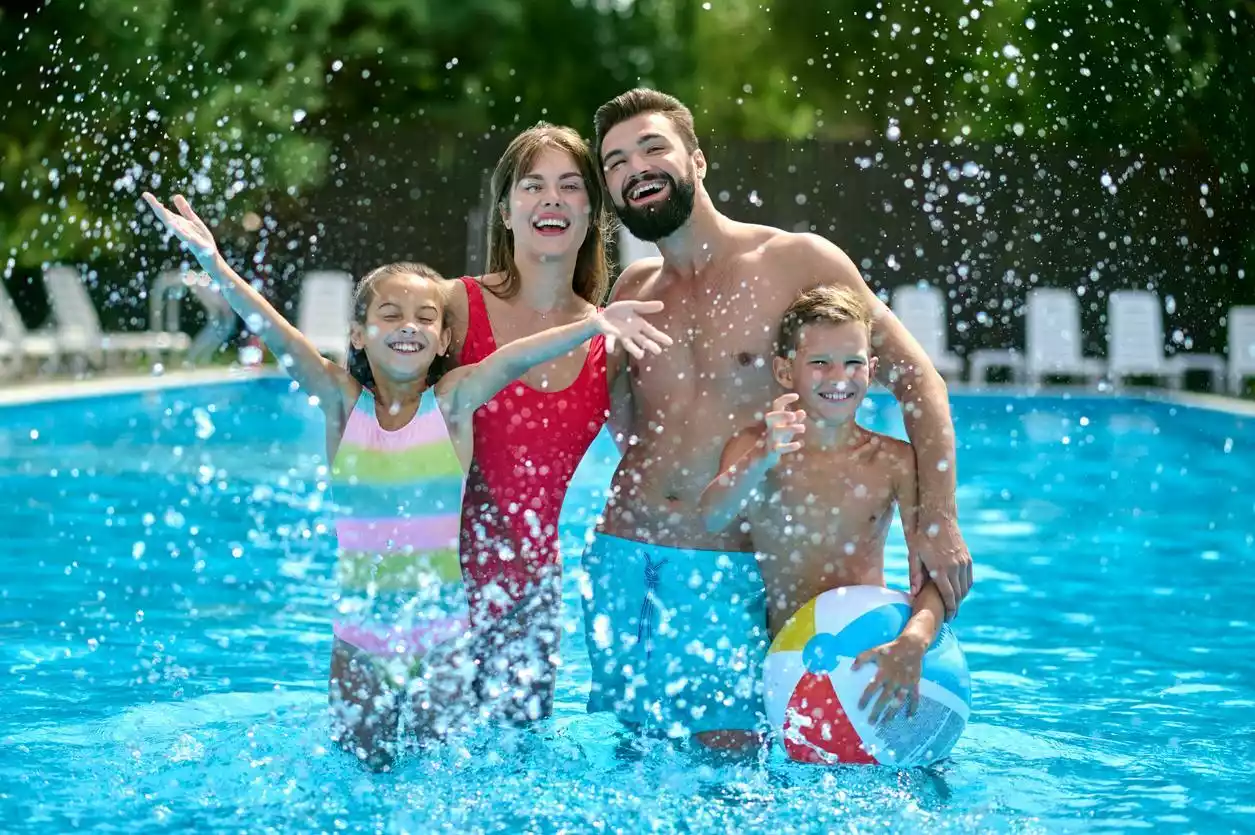 Family of four standing in and enjoying their home swimming pool. 