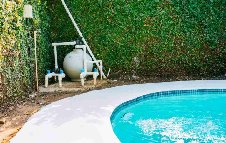 A pool pump with a sand filter sits in the corner near the swimming pool.