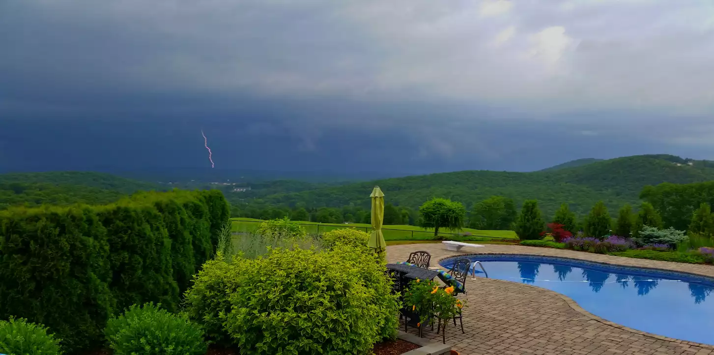 A view of a distant lightning strike in a dark, cloudy, distant sky.